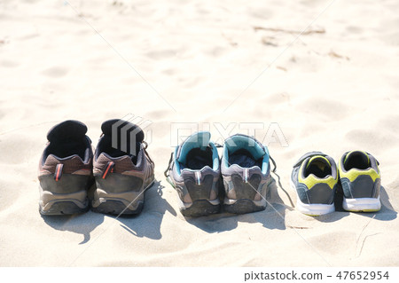 Three pairs of sneakers are on the sand. The concept of the weekend Three pairs of sneakers are on the sand. The concept of the weekend 47652954