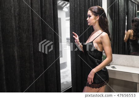 Brunette Woman Looking out of room window 47656553
