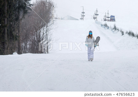 Young girl snowboarder goes towards camera on snowy mountain in the forest 47656623