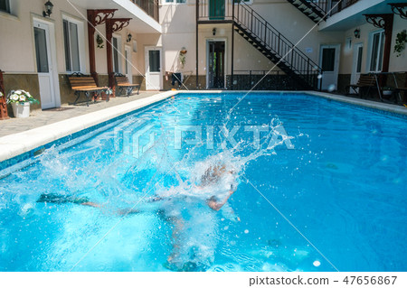 Six-year-old boy diving underwater into the pool in swimming trunks, flippers and swimming goggles 47656867