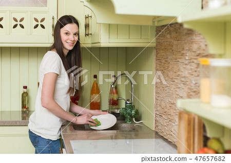 Happy young woman washing dishes in the kitchen 47657682