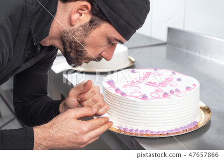 Handsome professional confectioner making a delicious cake in the pastry shop. Handsome professional confectioner making a delicious cake in the pastry shop. 47657866