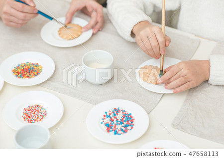 Mom and her daughter baking together and decorating the cookies Mom and her daughter baking together and decorating the cookies 47658113