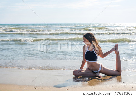 Woman in bikini practice yoga Eka Pada Rajakapotasana Royal pigeon Pose at seaside. Woman in bikini practice yoga Eka Pada Rajakapotasana Royal pigeon Pose at seaside. 47658363