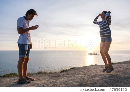 Couple fun pastime on a mountain with seaside view. Man and woman dance together at sunset Side view Couple fun pastime on a mountain with seaside view. Man and woman dance together at sunset Side view 47659130