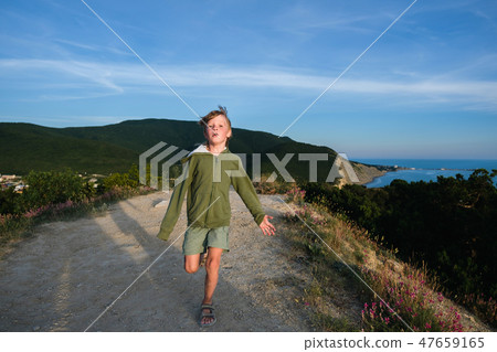 Six year old boy running on a mountain road at sunset with town and sea view. Cool summer evening. Six year old boy running on a mountain road at sunset with town and sea view. Cool summer evening. 47659165