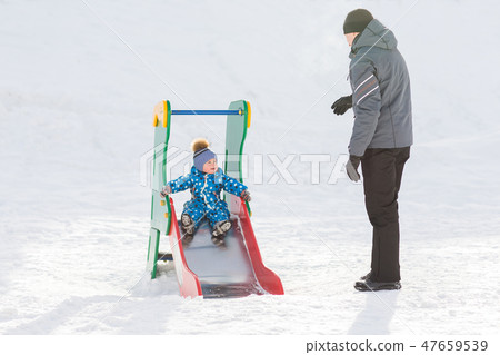 Dad walks with his son in the winter and rolled down the hill Dad walks with his son in the winter and rolled down the hill 47659539