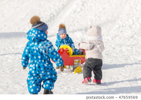 Children twin brothers walking in winter with playing with other children 47659569
