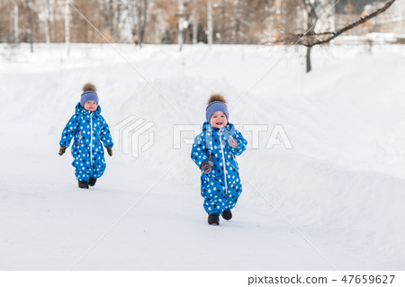 Twin boys walking in the Park in the winter in matching jumpsuits 47659627
