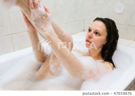 Woman washing leg in bath at home. 47659876