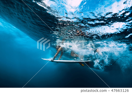 Surfer girl with surfboard dive underwater 47663126
