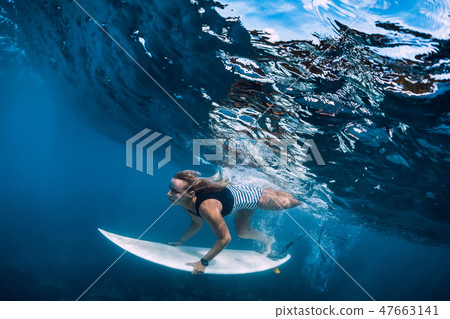 Surfer girl dive underwater. Surfer dive under Surfer girl dive underwater. Surfer dive under 47663141
