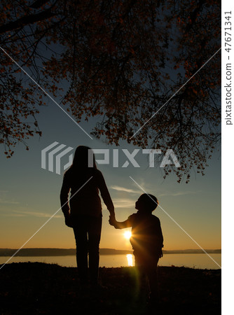 Brother and sister at sunset go holding hands Brother and sister at sunset go holding hands 47671341