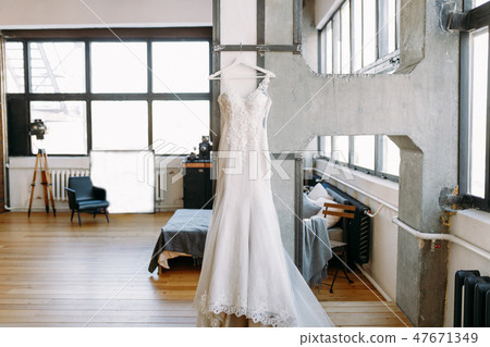 Beautiful women wedding dress weighs on the hangers in the big hall on the wall 47671349