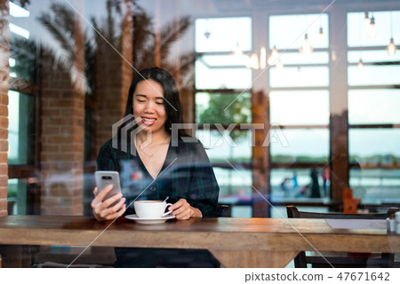 Girl having coffee and using phone in the bar Girl having coffee and using phone in the bar 47671642