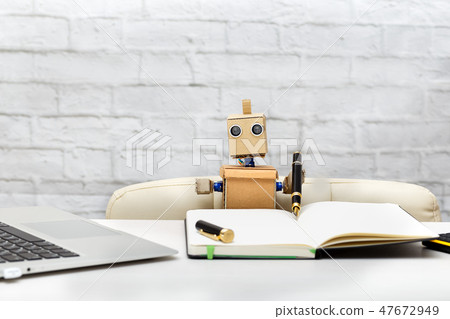 robot is sitting at the table, working place 47672949
