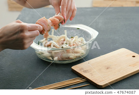 Closeup woman's hands cooking marinated shashlik or shish kebab, chicken meat on wooden skewer with Closeup woman's hands cooking marinated shashlik or shish kebab, chicken meat on wooden skewer with 47674087