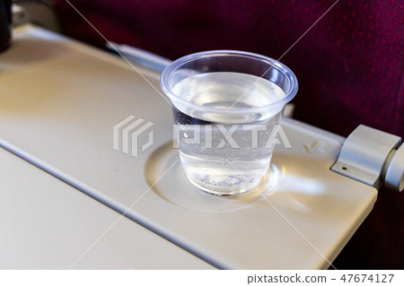 Inflight cabin glass of water on table. Inflight cabin glass of water on table. 47674127