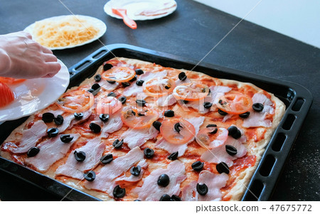 Cook preparing pizza. Closeup woman's hands put tomato to dough with sauce and bacon. 47675772