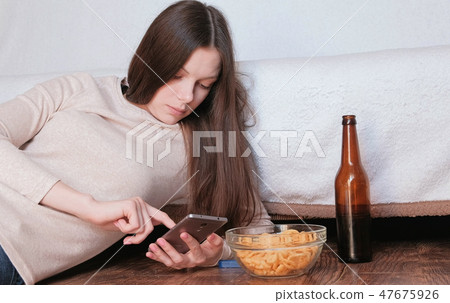 Sad young beautiful brunette woman typing a message on the mobile phone. Sad young beautiful brunette woman typing a message on the mobile phone. 47675926