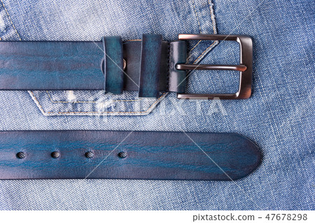 Belt lying on blue jeans. 47678298