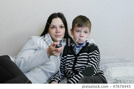 Watching TV lying on the couch. Mom and son watch TV together and smile. 47678445