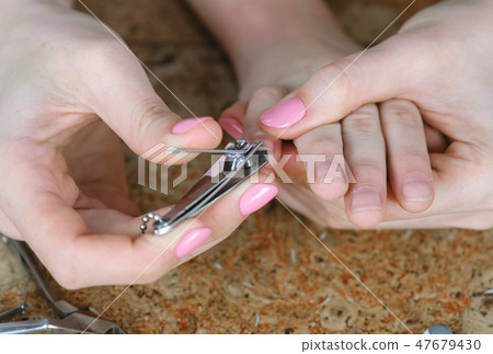 Mum is cutting nails to her son by Clippers on wood backgound. Close-up hands. Manicure for kid. Mum is cutting nails to her son by Clippers on wood backgound. Close-up hands. Manicure for kid. 47679430