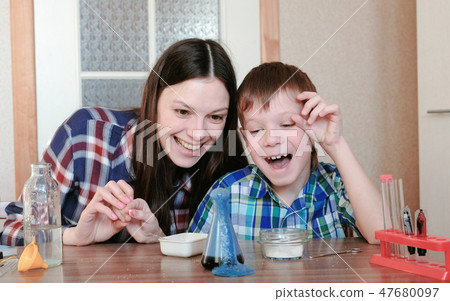 Chemistry experiments at home. Happy Mom and son make a chemical reaction with the release of gas in Chemistry experiments at home. Happy Mom and son make a chemical reaction with the release of gas in 47680097