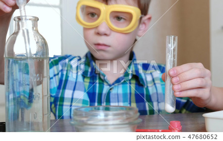 Experiments on chemistry at home. Boy pours blue liquid from a jar into a beaker with a pipette. 47680652