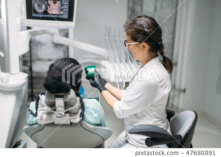 Dentist shows dentures to woman in a dental chair 47680891