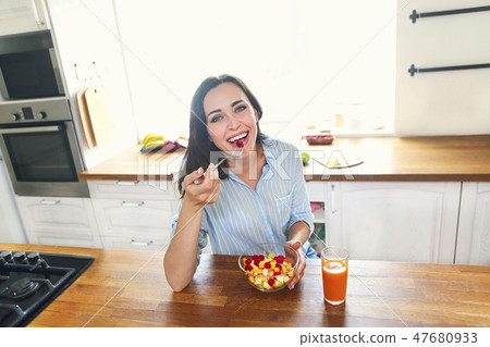 Young housewife eating fresh fruit salad Young housewife eating fresh fruit salad 47680933