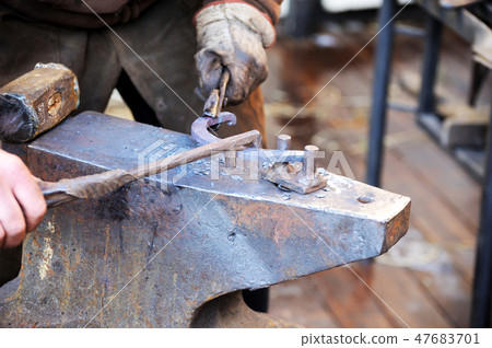 Blacksmith working metal with hammer on the anvil 47683701
