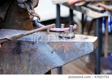 Blacksmith working metal with hammer on the anvil 47683702