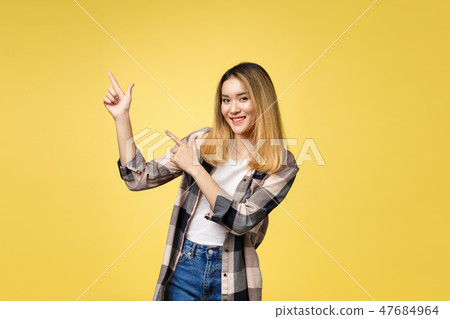 Smiling woman pointing finger side. Isolated portrait on yellow. Smiling woman pointing finger side. Isolated portrait on yellow. 47684964
