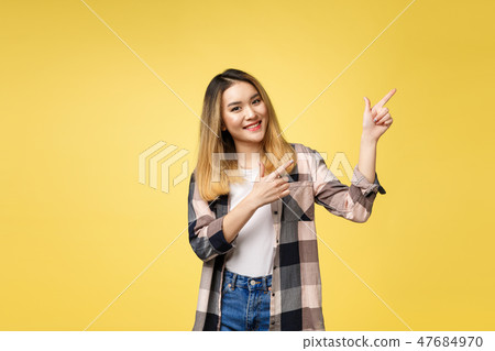 Smiling woman pointing finger side. Isolated portrait on yellow. Smiling woman pointing finger side. Isolated portrait on yellow. 47684970