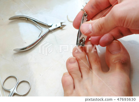 Man cutting toenails with clipper. Male cut toenails on foot. Foot and toes close-up. Top view. 47693630