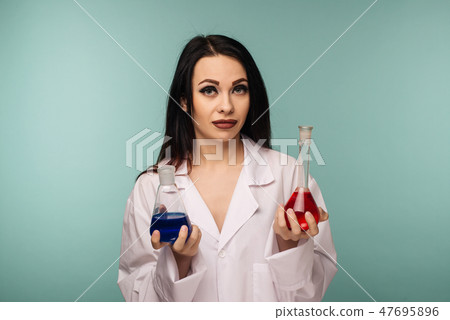 Portrait of female scientist examining flasks with different chemicals in medical lab Portrait of female scientist examining flasks with different chemicals in medical lab 47695896