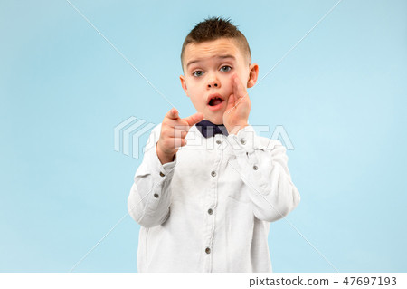 The teen boy whispering a secret behind her hand over blue background The teen boy whispering a secret behind her hand over blue background 47697193