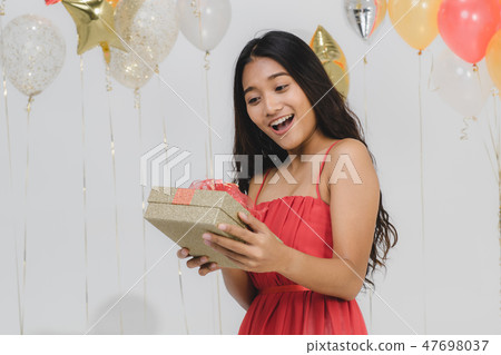 Girl in red dress with gift box at party. Girl in red dress with gift box at party. 47698037