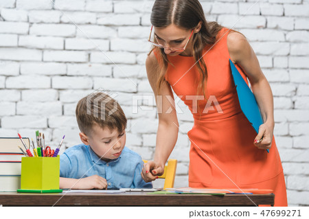 Student boy doing work in school supervised by his teacher 47699271