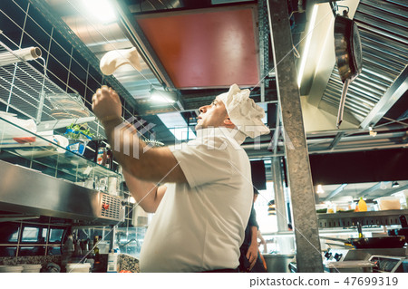 Cook tossing dough while preparing pizza in a modern Italian restaurant Cook tossing dough while preparing pizza in a modern Italian restaurant 47699319