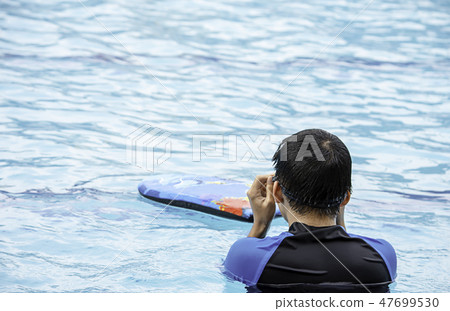Asean boys are swimming in the pool. 47699530