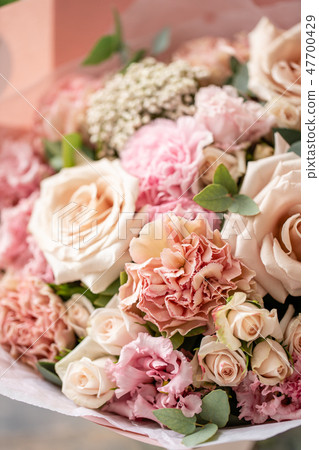 beautiful fresh cut bouquet of mixed flowers in vase on wooden table. The work of the florist at a 47700429