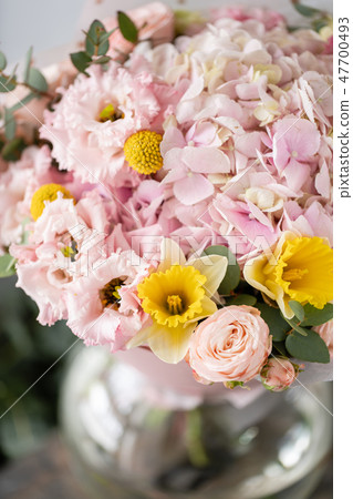 beautiful fresh cut bouquet of mixed flowers in vase on wooden table. The work of the florist at a 47700493