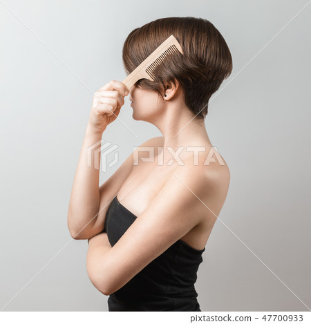 Woman brushing her hair with a wooden comb 47700933