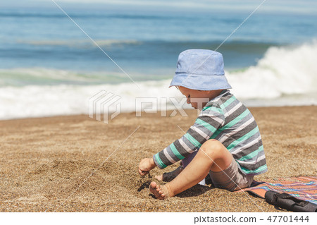Little boy with cute hat playing with sand Little boy with cute hat playing with sand 47701444