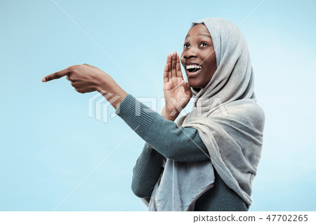 The young african woman whispering a secret behind her hand over blue background The young african woman whispering a secret behind her hand over blue background 47702265