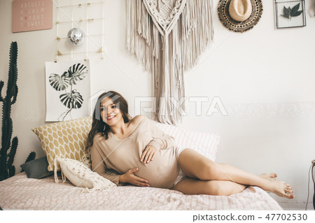 Beautiful young pregnant woman at home lying in bed 47702530