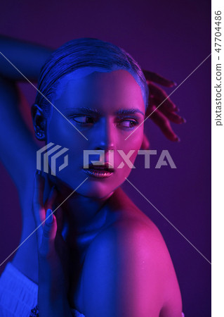 Glitter Neon Lights on Skin of Sexy Young Model in Photo Studio 47704486