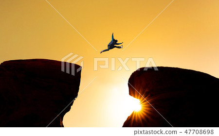 Silhouette a man jumping over precipice 47708698